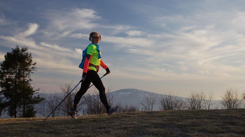 Zdjęcie Katarzyny Daniek idącej z kijami do nordic walking. W tle Beskidy